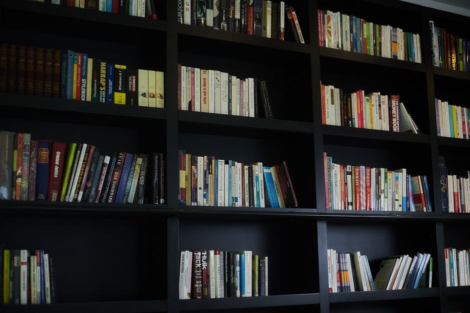 A wide array of books neatly organized on dark modern shelves in an indoor library setting.